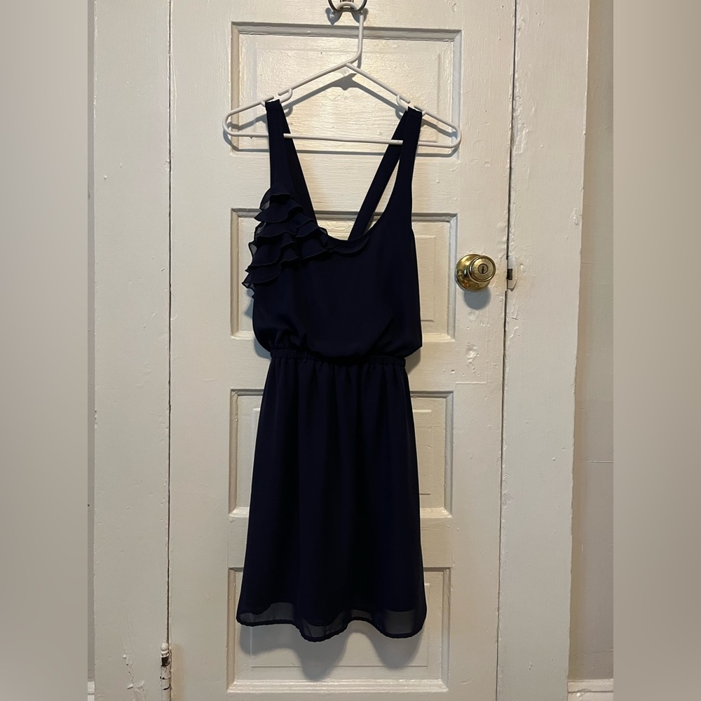 Timeless blue cross back cocktail dress with ruffle. Comfortable, wrinkle free.
